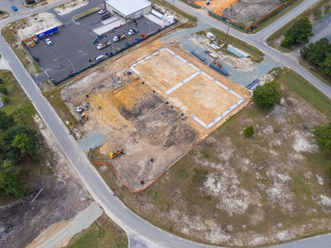 Aerial view of a construction site with concrete foundations, heavy machinery, and earthworks in Leland, North Carolina, United States.