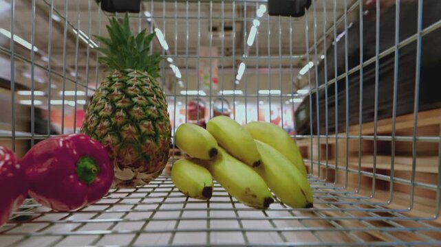 Timelapse of a shopping cart filled with fresh fruits moving through a supermarket. Grocery shopping, healthy lifestyle, fresh produce, nutrition, consumer habits and everyday shopping experience.