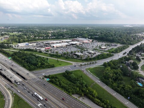 Aerial view of a shopping center complex situated near a highway interchange with surrounding green spaces and residential areas in Crestview Hills, Kentucky, United States.