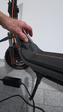 Man Plugging Charger Cable into Electric Scooter Port