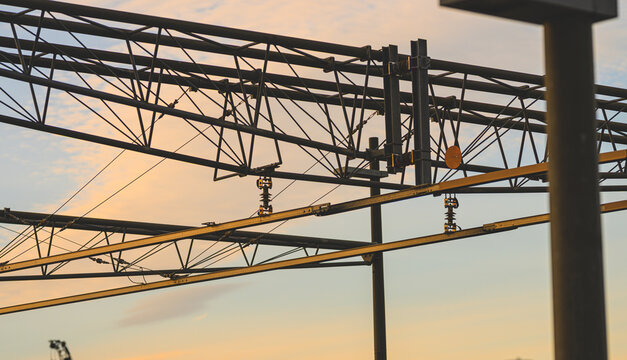 Complex railway power lines and steel gantries at dusk.