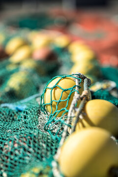 Yellow fishing float caught inside weathered green netting.