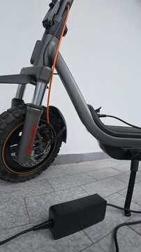 Electric Scooter Connected to Power Adapter Charging Outdoors