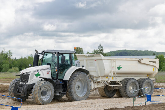 Nancy, France - May 23rd 2021 : View on a white tractor Massey Ferguson MF 7720 S with a white dump trailer for earthworks on a construction site.