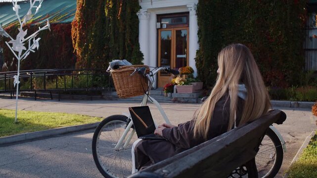 Young woman blogger works on laptop as sits in autumn park