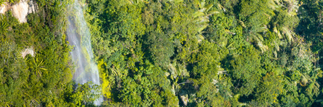Aerial view of La Chaquira waterfall cascading down a lush green canyon wall surrounded by dense tropical vegetation in San Agustin, Huila, Colombia.
