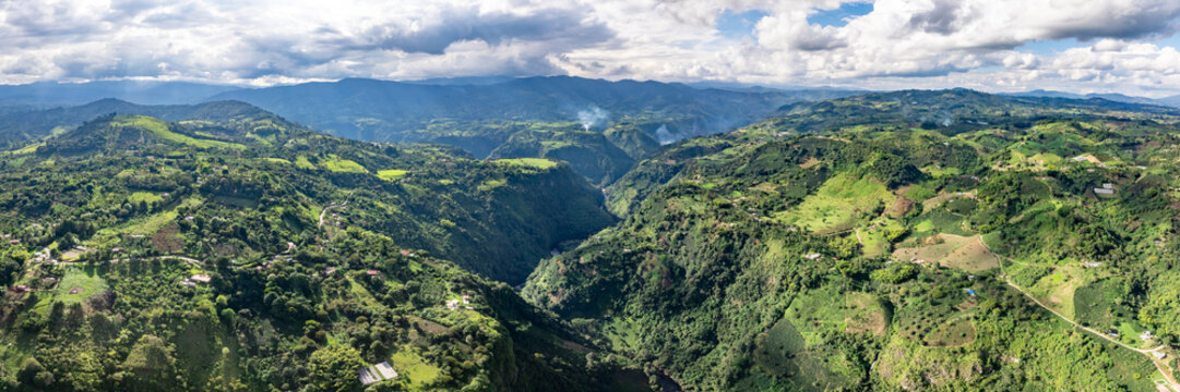Aerial view of La Chaquira and the lush green canyon landscape with rolling hills, dense vegetation, and winding river paths in San Agustin, Huila, Colombia.