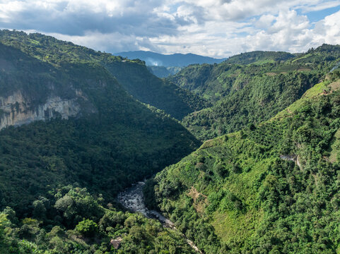 Aerial view of La Chaquira canyon with lush green mountains, steep cliffs, and a winding river below in San Agustin, Huila, Colombia.