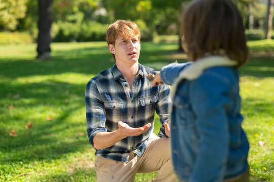 Father kneeling talking with son in park