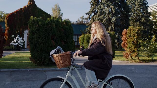 Cheerful woman with blonde hair rides bicycle in autumn park