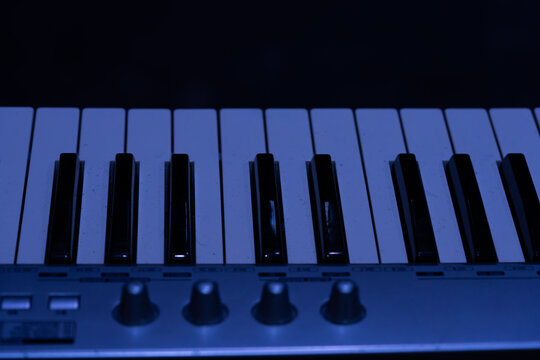 Detail of digital synthesizer keys in blue spotlight for concert concept