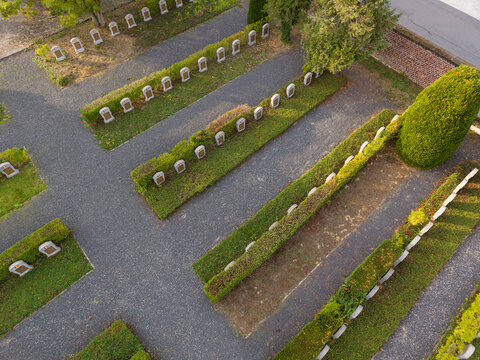 Aerial view of Eppegem Military Cemetery with rows of white war graves set among manicured hedges and gravel paths in Zemst, Flanders, Belgium.