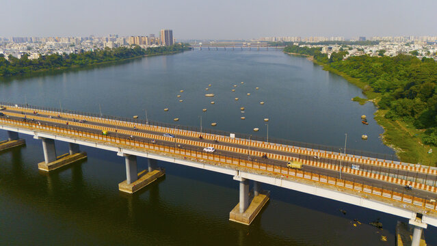 Aerial view of the bridge over the Tapi River with traffic moving across the structure, surrounded by urban development and greenery along the riverbanks in Surat, Gujarat, India.