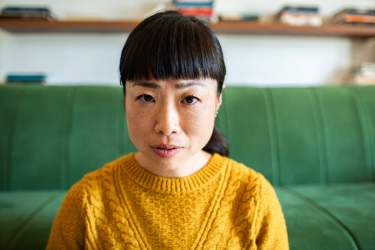 Woman looking at camera on green sofa at home