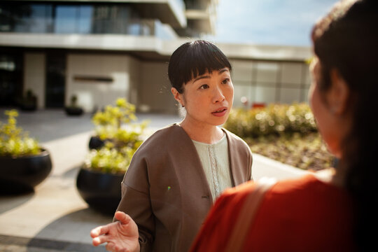 Woman gestures while talking to another person outdoors