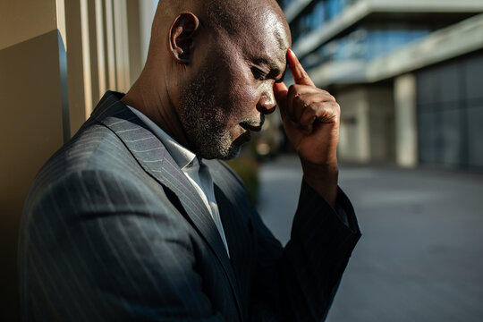 Stressed businessman touching forehead outside office building