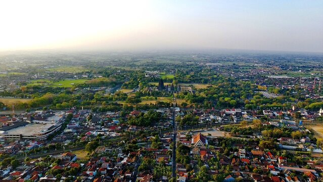 Aerial view of the historic Bokoharjo temple complex surrounded by lush greenery, residential rooftops, and agricultural fields in Prambanan, Special Region of Yogyakarta, Indonesia.