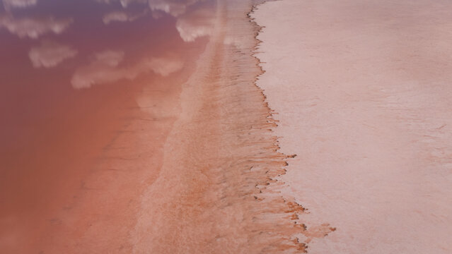 Aerial view of Hutt Lagoon, a vibrant pink lake with salt crust textures and reflections of clouds on the water surface in Yallabatharra, Western Australia, Australia.