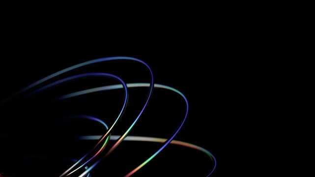 Thin iridescent wire loops orbiting on a dark background, energy flow and neural connection concept, seamless loop, 3d rendered animation
