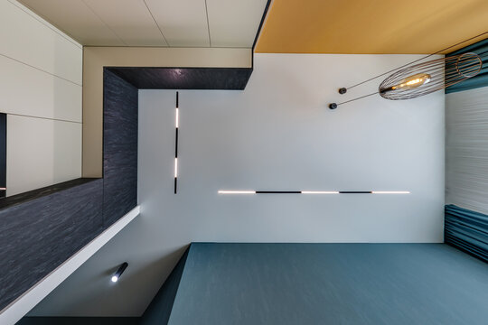 suspended ceiling with halogen spots lamps and drywall construction in empty room in apartment or house. Stretch ceiling white and complex shape.