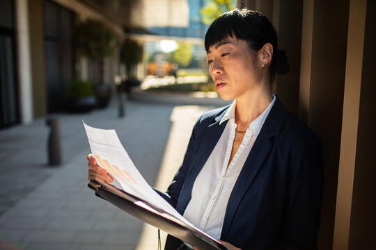 Businesswoman reading report outside an office building