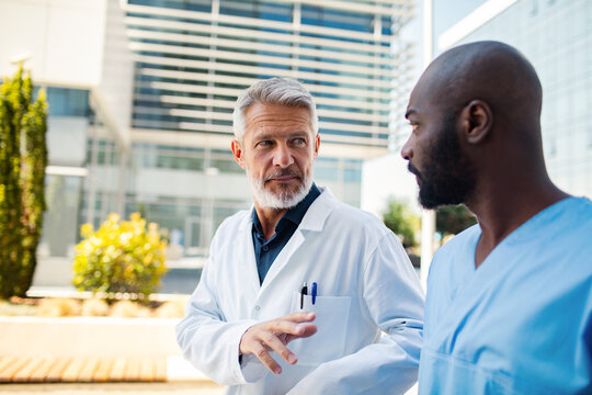 Senior doctor mentoring colleague outside hospital