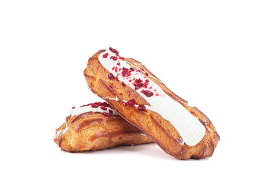 Two eclairs with white icing and dried cranberry pieces isolated on white background. French pastry, dessert and bakery concept.
