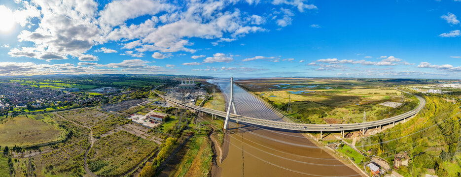 Deeside, Wales, United Kingdom - 11 October 2026: Aerial view of the Flintshire Bridge spanning the River Dee, with industrial areas, marshlands, and green fields under a bright blue sky.
