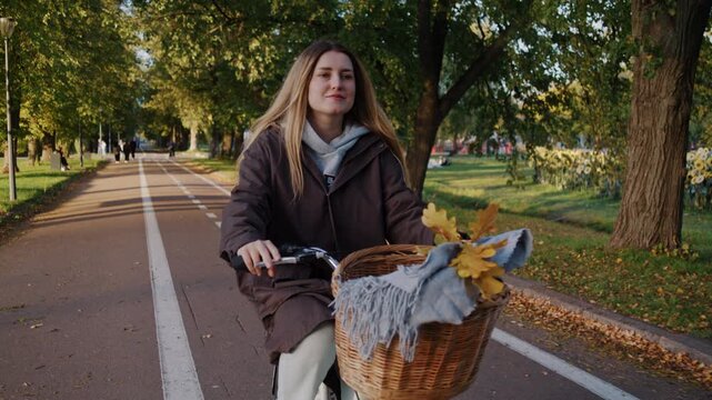 Positive woman cyclist enjoys ride along quiet park road