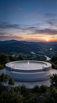 Modern circular observation deck overlooking a serene river valley at sunset offering panoramic mountain views