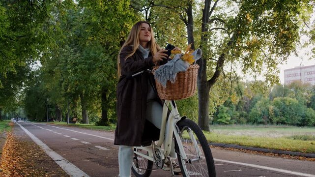 Happy woman reads message on smartphone as leans on bicycle