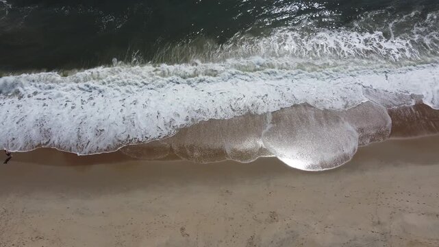 Top-down ocean waves washing onto sandy beach near Lewes Delaware