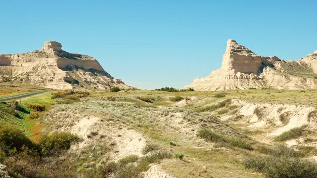 Road view of asphalt highway winding toward towering sandstone bluffs at Scotts Bluff National Monument in Gering, Scotts Bluff County, Nebraska