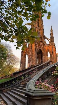 Low-angle shot of the historic Scott Monument in Edinburgh during a golden autumn sunset.