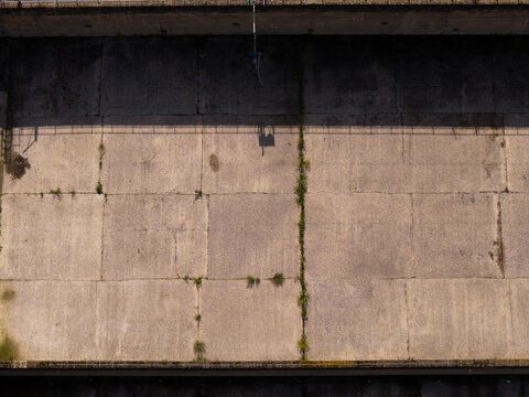 Isleworth, United Kingdom - 01 October 2026: Aerial view of concrete surfaces at Mogden Sewage Water Treatment Works with visible expansion joints and weeds growing in the cracks.