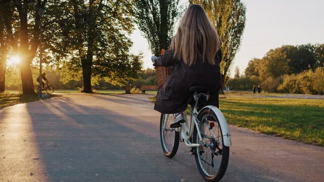 Woman follows smooth paved path as rides through autumn park
