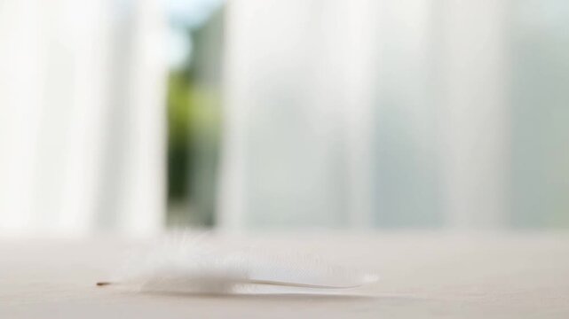 Thin white sheet falls and settles across a pale tabletop in a bright interior