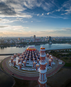 Kecamatan Mariso, Indonesia - 25 June 2024: Aerial view of Masjid Kubah 99 Asmaul Husna with its colorful domes and tall minaret, situated by the waterfront in Sulawesi Selatan under a sunset sky.