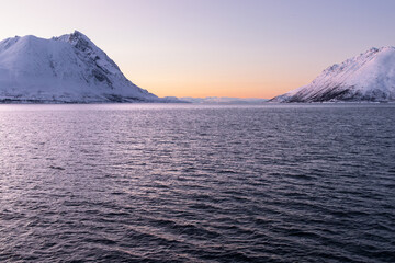 Golden polar night sunset glowing over an arctic fjord between snowy mountains in Northern Norway © Alberto