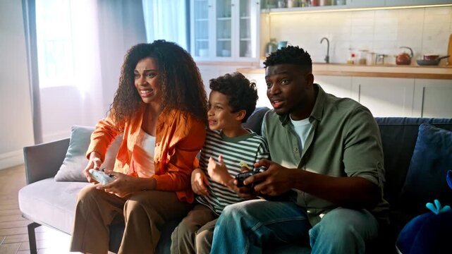 Happy black family playing video game home sofa. Parents son high five win joy.