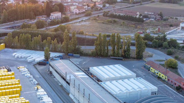 Pontenure, Italy - 02 October 2026: Aerial view of the Xella production plant with industrial warehouses, stacked construction materials, and surrounding trees in Emilia-Romagna.