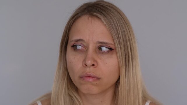 Anxious young blonde woman reacting to sudden sound with fearful suspicious expression, quickly moving her eyes as if startled by something unseen