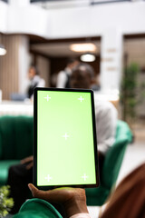 Green screen, tablet and hotel lounge as blank device dominates foreground before blurred seated guest. Digital advertising, screen replacement and mockup enable content placement in reception area. © DC Studio