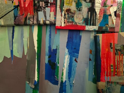Two collage panels with red torn paper and scribbled drawings sit above torn vertical strips in blue, green, mint and mauve. A red linen-framed panel rises at the right.