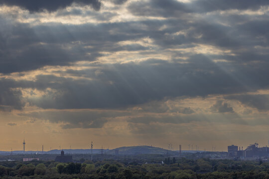 High-angle urban landscape from industrial rooftop dome over green forest canopy white residential apartment blocks slag heap hill and skyline horizon in Duisburg Ruhr region
