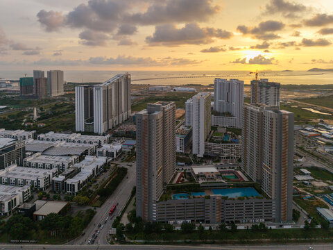 Simpang Ampat, Penang, Malaysia - 05 October 2026: Aerial view of Batu Kawan featuring modern high-rise residential towers, a podium swimming pool, and urban infrastructure under a golden sunset sky.