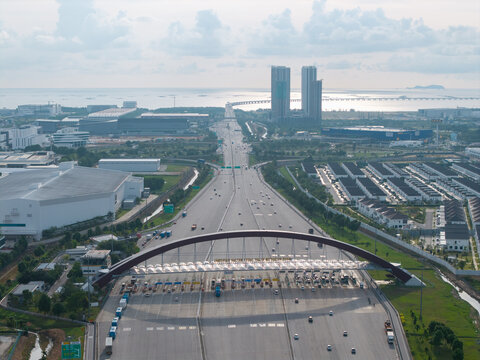 Simpang Ampat, Malaysia - 05 October 2026: Aerial view of Plaza Tol Bandar Cassia with its arched structure spanning the highway, surrounded by industrial buildings and residential areas.