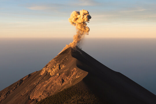 Fuego volcano releasing ash cloud at golden hour, Guatemala