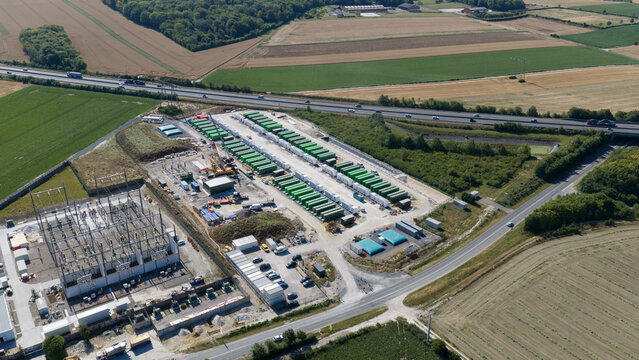 Saleux, Hauts-de-France, France - 08 July 2026: Aerial view of a battery storage facility with green containers and an electrical substation near a highway and agricultural fields.