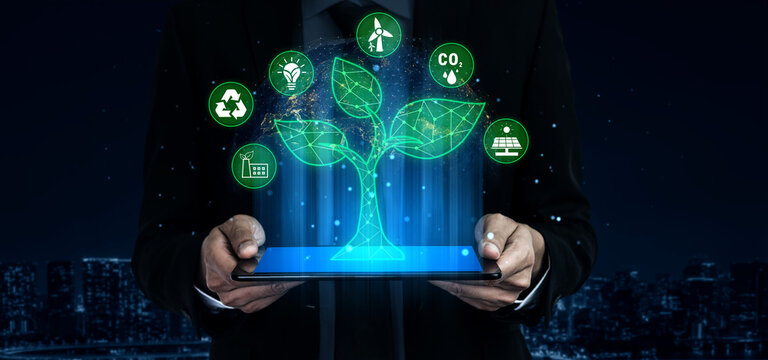 Businessman Holding Tablet with Digital Green Tree and Eco-Friendly Icons, Symbolizing Sustainable Technology and Environmental Solutions Quark.
